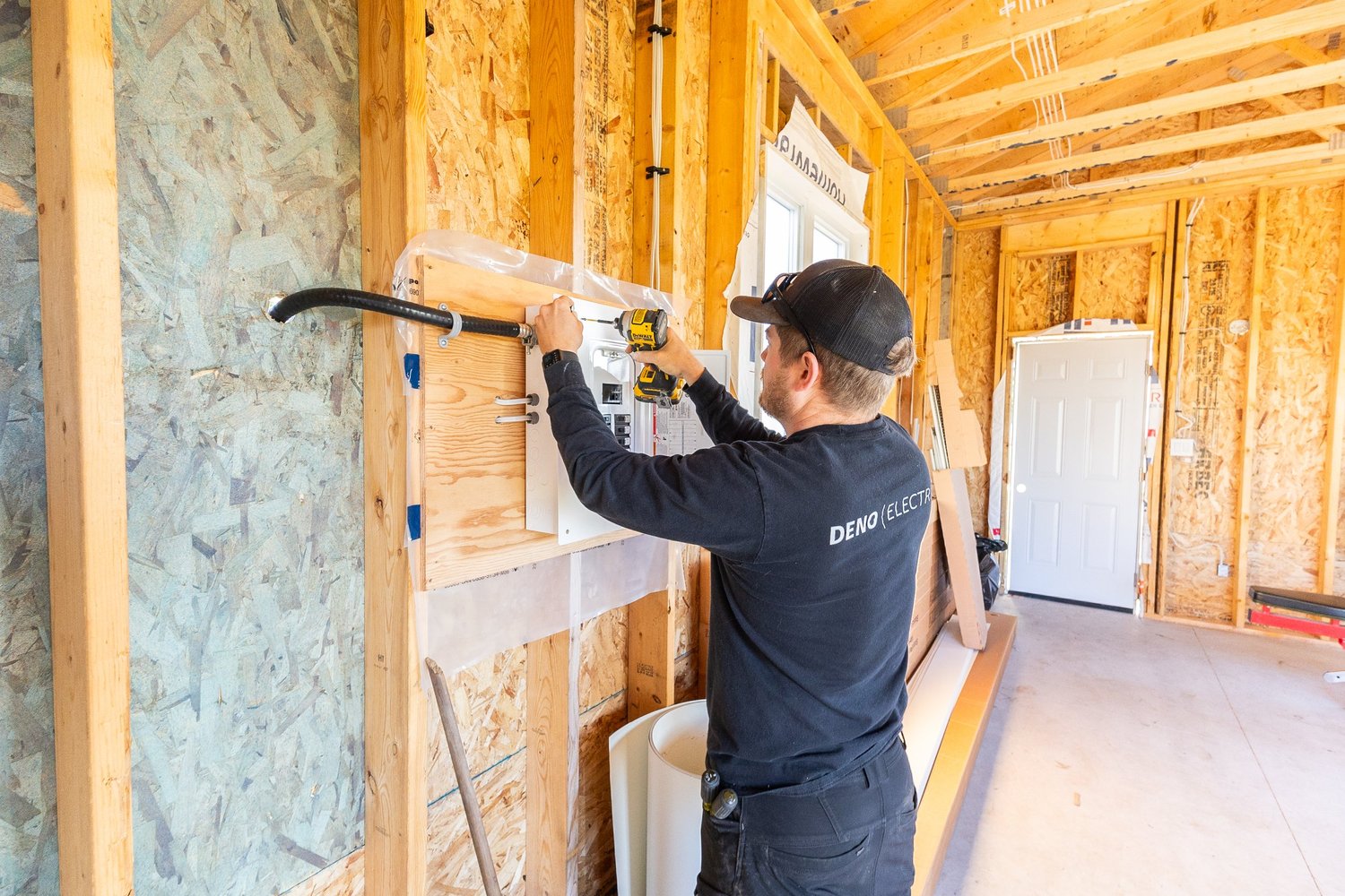 A Deno electrician installing an electrical panel in a building under construction.
