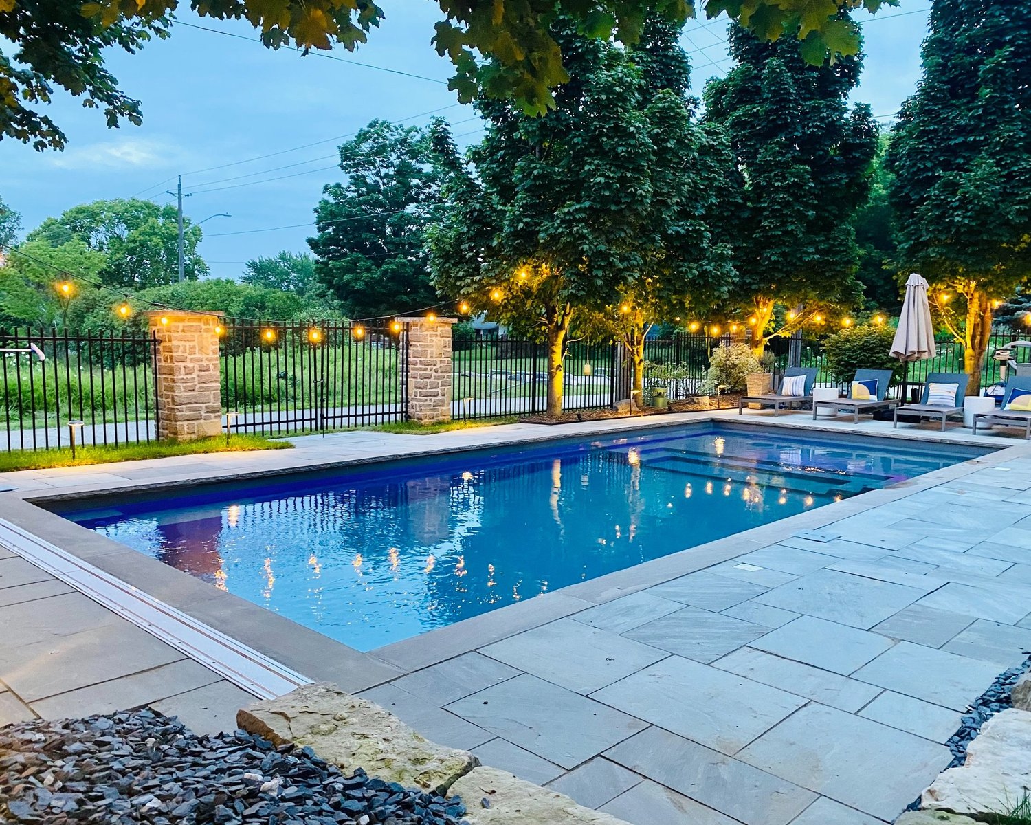 A poolside patio with illuminated trees and string lights from Deno’s portfolio.