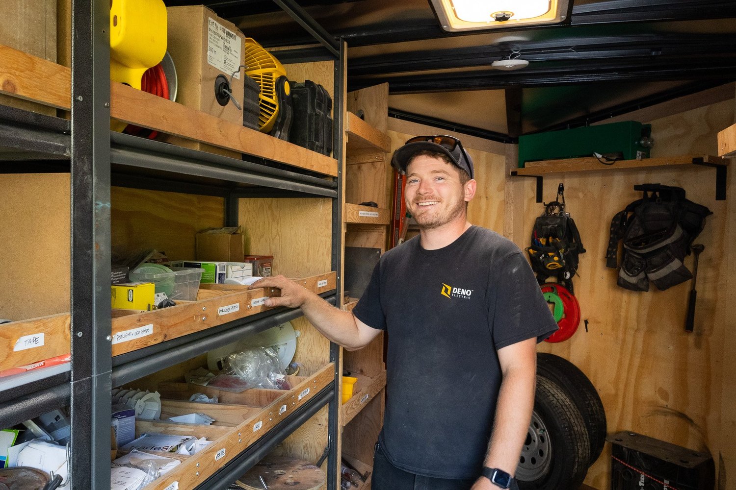 Zachary Denomme, founder of Deno Electric, standing in a work trailer.